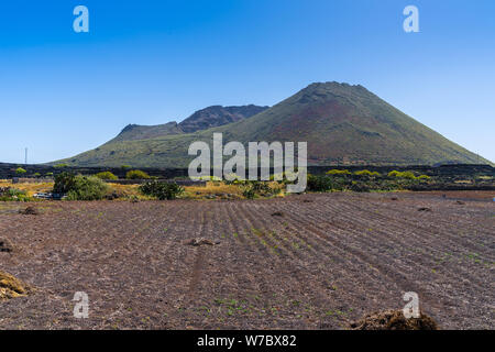 L'Espagne, Lanzarote, majestueux volcan mont corona derrière brown acres Banque D'Images