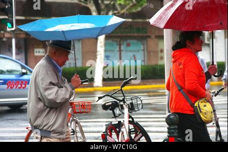 Les piétons tentent de se protéger avec des parasols de fort vent et les fortes pluies causées par le typhon Khanun à Shanghai, Chine, 15 octobre 2017. Ch Banque D'Images