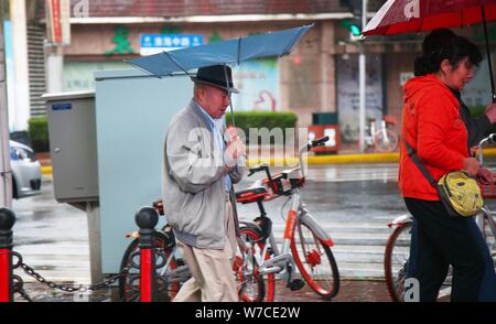 Les piétons tentent de se protéger avec des parasols de fort vent et les fortes pluies causées par le typhon Khanun à Shanghai, Chine, 15 octobre 2017. Ch Banque D'Images