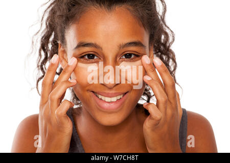 Une jeune femme à la peau sombre s'applique un cache-cernes sous les yeux avec ses doigts Banque D'Images