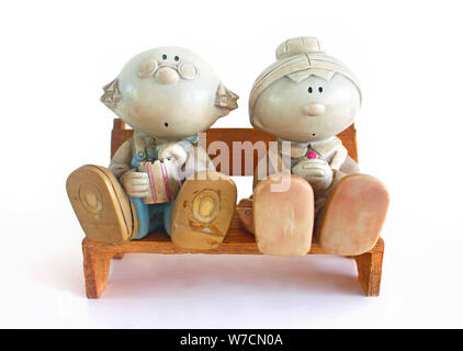 Figurine de couple âgé assise sur un banc en bois, sur fond blanc. Banque D'Images