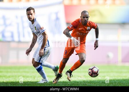 Joueur de football brésilien, Diego Tardelli de Shandong Luneng Taishan, droit, dribble le ballon contre un joueur de football espagnol Mario Suarez de Guizhou Banque D'Images