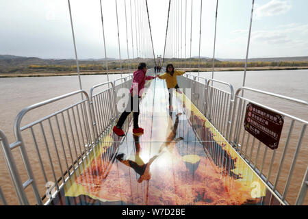 Des touristes posent pour des photos sur la vitre 3D-bas pont sur le fleuve Jaune en Zhongwei ville, nord-ouest de la Chine, région autonome du Ningxia Hui, 21 O Banque D'Images