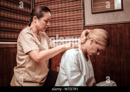 Masseuse professionnelle faire son massage du cou du client. Banque D'Images