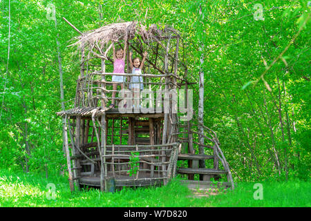 Deux petites filles heureux dans une maison de l'arbre en bois sur une journée ensoleillée. Les soeurs se réjouissent de l'été. Le concept de l'été. Banque D'Images