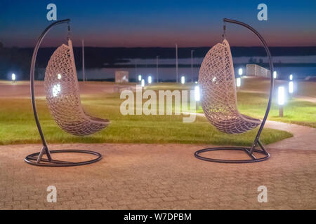 La Russie, Bolgar - Juin 08, 2019 Gali Kol Resort&Spa : Deux rotin chaises en osier suspendu contre la mer contre le coucher du soleil, l'été. Banque D'Images