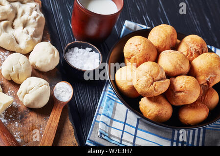 Close-up of Jamaican poêlée de quenelles sans levain dans un bol noir sur une table en bois avec des ingrédients sur une planche en bois, vue horizontale d'en haut Banque D'Images