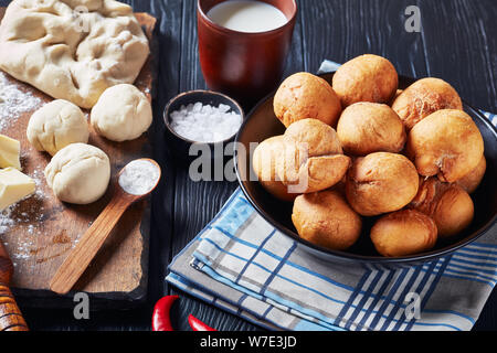 Jamaican fried dumplings sans levain dans un bol noir sur une table en bois avec des ingrédients sur une planche en bois, vue horizontale à partir de ci-dessus, close-up Banque D'Images