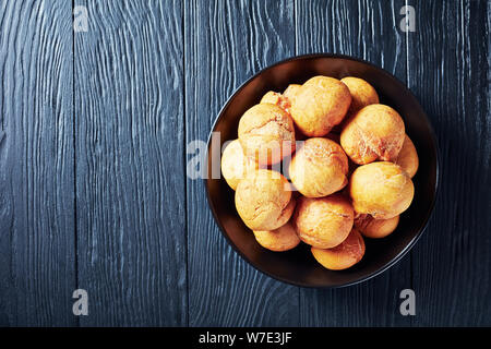 Jamaican fried dumplings sans levain dans un bol noir sur une table de bois, vue horizontale à partir de ci-dessus, close-up, mise à plat Banque D'Images