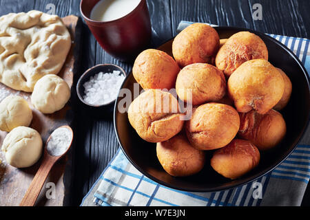 Boulettes frites jamaïcaine dans un bol noir sur une table en bois avec des ingrédients sur une planche en bois, vue horizontale à partir de ci-dessus, close-up Banque D'Images