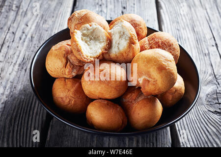 Caraïbes poêlée de quenelles sans levain dans un bol noir sur une vieille table rustique en bois, vue horizontale à partir de ci-dessus, close-up Banque D'Images