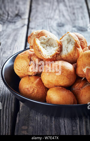 Jamaican fried dumplings sans levain dans un bol noir sur une vieille table rustique en bois vertical, vue de dessus Banque D'Images