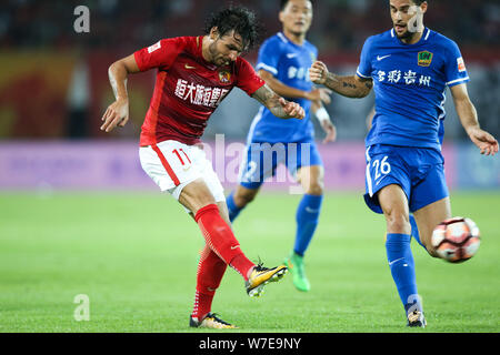 Joueur de football brésilien Ricardo Goulart, gauche, de Guangzhou Evergrande frappe la balle pour faire une passe contre un joueur de football espagnol Mario Suarez de Banque D'Images