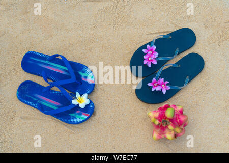 Tongs colorés sur la plage de sable. Homme et femme chaussons. Le concept de l'amour et de vacances romance. Banque D'Images