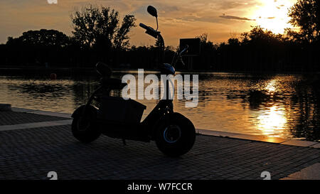 Coucher de soleil sur la base d'aviron avec scooter électrique Banque D'Images