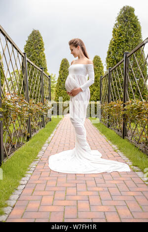 Une belle et facile la grossesse. Un long train blanc du ventre d'une belle jeune fille enceinte outdoor Banque D'Images