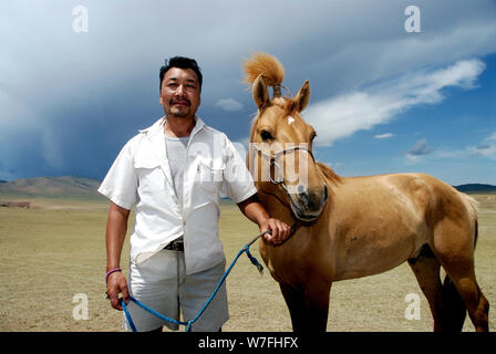 Un nomade mongol pose fièrement avec son cheval pendant le festival Naadam Banque D'Images