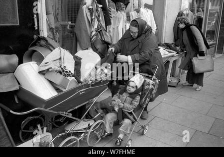 Pauvreté des années 1970 Royaume-Uni. Race mixte de la famille de la classe ouvrière mère et l'enfant dehors faire du shopping acheter de vieux vêtements d'occasion Battersea sud de Londres 70s 1979 Angleterre HOMER SYKES Banque D'Images