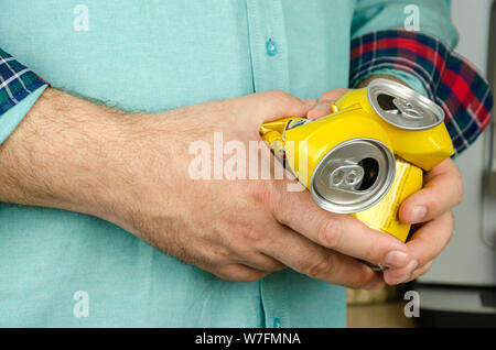 Man's hands holding deux canettes de bière vides froissés Banque D'Images