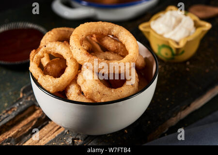 Libre d'un bol en céramique blanc avec quelques calamares a la romana, Fried squid battues typique de l'Espagne, les anneaux sur une table en bois rustique à côté d'une Banque D'Images