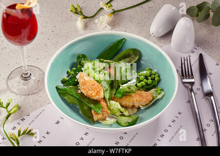 Tranches de poulet pané frit dans une assiette bleue servi sur une table avec une nappe blanche. Banque D'Images