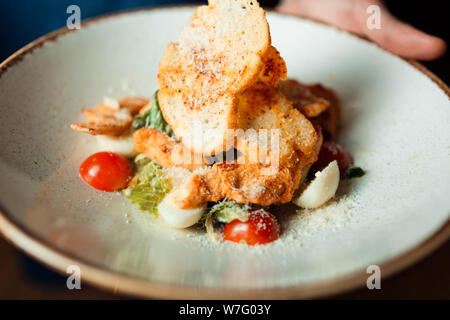 Salade César classique sur un plat avec des croûtons, du poulet, des œufs et des tomates. Banque D'Images