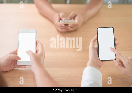 Groupe d'amis holding Smartphone avec écran vide sur la table dans le café. Prenez votre écran pour mettre sur la publicité. Banque D'Images