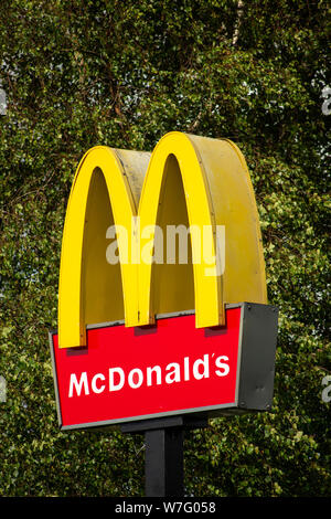 Logo de marque McDonald's signé sur fond d'arbre vert comme juxtaposition contrastée Banque D'Images