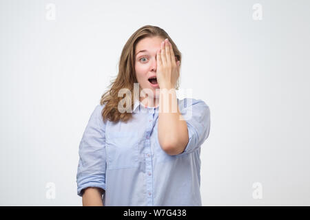 Belle jeune femme un œil avec la main contrôle de sa vue. Du visage positif l'émotion humaine. Banque D'Images