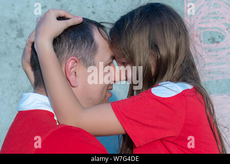 Fille câlins papa. Père et fille en rouge. Notion de plaisir le jour de père. Banque D'Images