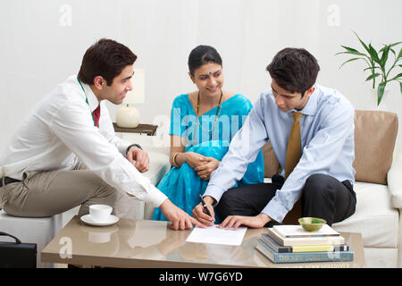 Jeune couple signant des documents avec un conseiller financier Banque D'Images