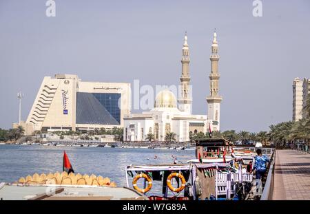 Bateaux touristiques vous attendent les clients au ruisseau au centre-ville de Sharjah. Dans l'arrière-plan vous pouvez voir un hôtel (Radisson Blu Resort) et une mosquée (mosquée Al-Maghfirah). (14 janvier 2019) | dans le monde entier Banque D'Images