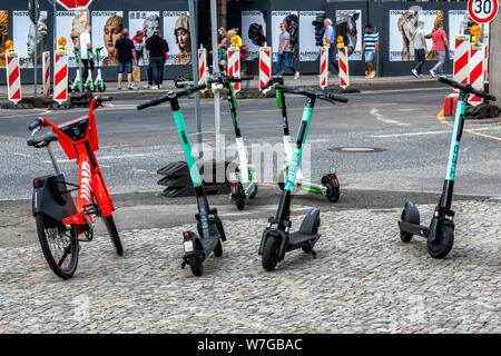 Deux roues électriques. E-scooters et vélos à piles encombrent les trottoirs de la ville dans l'avenue Unter den Linden, Mitte, Berlin.Les entreprises rivales en compétition pour l'espace sur les trottoirs de la ville Banque D'Images