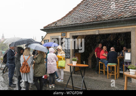 Les gens de prendre un verre dans l'extérieur de la pluie avec parapluie et imperméables à Würzburg, Allemagne Banque D'Images