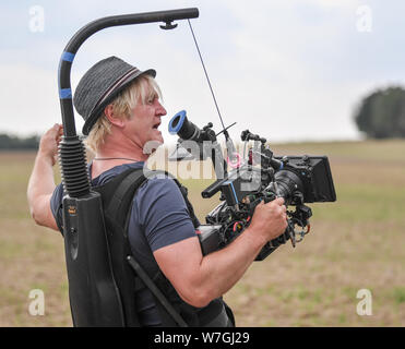 Reichenow, Allemagne. Le 06 août, 2019. Detlev Buck directeur est avec une caméra à l'événement de la presse sur l'ensemble de l'Amazonie série Bibi et Tina. Le tournage de la nouvelle Amazon Bibi Original & Tina est actuellement en cours dans la région de Berlin. La série live action pour toute la famille accompagne la jeune sorcière Bibi Blocksberg et sa meilleure amie Tina sur leurs aventures à l'Reiterhof. Crédit : Patrick Pleul/dpa-Zentralbild/dpa/Alamy Live News Banque D'Images