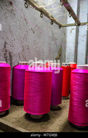 Rose coloré des bobines de fil pour un métier à tisser d'attendre l'utilisation, Varanasi, Inde Banque D'Images