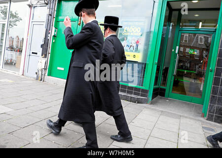 Vue arrière des deux hommes juifs hassidiques de marcher le long de Stamford Hill high street, dans le nord de London N16 England UK KATHY DEWITT Banque D'Images