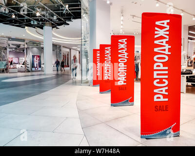 Rabais saisonniers dans le magasin. Bannières rouge avec texte vente sur le russe et l'anglais langues officielles sur une vitrine à l'entrée de la boutique. Black Banque D'Images