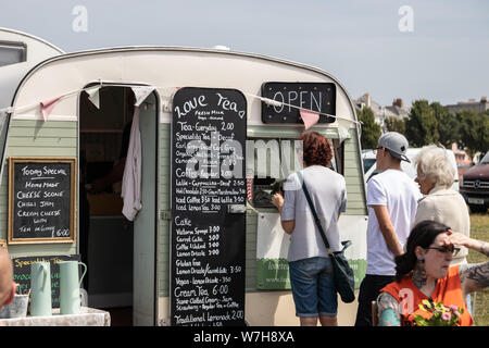 Les gens font la queue pour le thé et café dans une caravane vintage transformé en un café mobile Banque D'Images