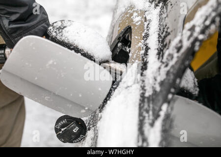 Détail sur l'homme son ravitaillement en carburant diesel en hiver, porte de réservoir de gaz couverte de neige. Banque D'Images