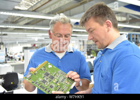Le contrôle de la qualité dans l'ingénierie dans le travail d'équipe - les employés lors d'une réunion - la production de l'électronique dans une usine industrielle moderne Banque D'Images