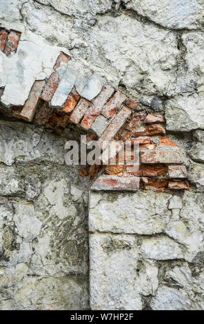 Partie de l'ancien mur en pierre grise avec des briques orange sur l'arche. Banque D'Images