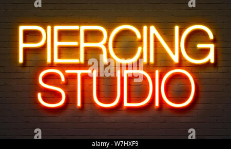 Studio de piercing en néon sur fond brique Banque D'Images