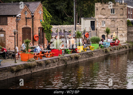 Cafés et restaurants : repas en dehors de l'eau à Cox's Yard avec le vieux Clopton Bridge Toll House dans l'arrière-plan. Banque D'Images