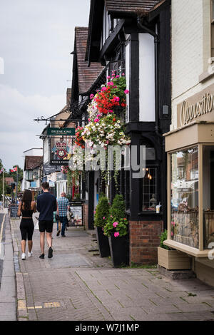 Cafés et restaurants. Une vue de la rue avec le mouton Rose and Crown Inn, suspensions de fleurs et d'un jeune couple en train de marcher. Banque D'Images