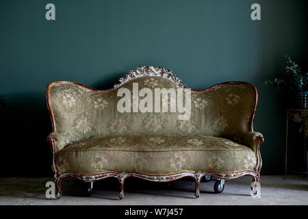 Table ancienne avec un bois, tissu rembourré. Contre le mur vert.intérieur rétro Banque D'Images