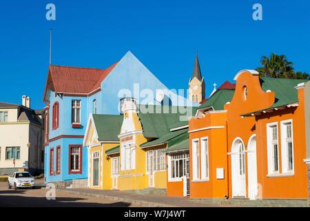 Maisons colorées de l'époque coloniale Allemande, derrière la tour de l'église de roche, vieille ville de Luderitz, en Namibie Banque D'Images