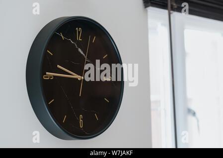 Gros plan d'une horloge noire sur un mur blanc dans une maison moderne Banque D'Images