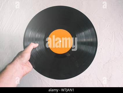 Vinyl record dans un homme de main. Un homme choisit la musique à écouter sur un lecteur de vinyle. Partie ou disco concept. Arrière-plan de la musique Banque D'Images