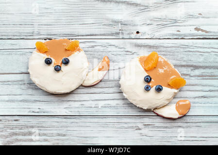 Fun food for kids. Gâteaux de riz en forme de renard couché sur un tableau blanc rustique. Fox est fabriqué à partir de fromage à la crème, beurre d'arachide, de tranches de pommes, oranges Banque D'Images